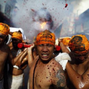 Devotees of the Chinese Jui Tui Shrine carry a statue through exploding firecrackers during the annual vegetarian festival procession through central Phuket